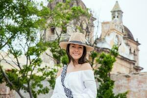 bellissimo giovane donna provando su cappelli per acquistare uno a partire dal un strada venditore nel cartagena de indie murato città foto