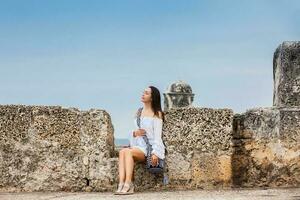 bellissimo donna su bianca vestito seduta solo a il muri circostante il coloniale città di cartagena de indie foto