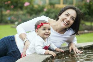 bambino ragazza e sua mamma giocando con acqua foto