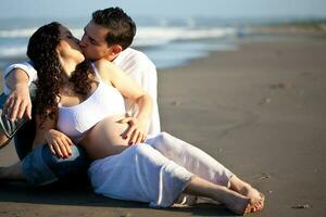 coppia a il spiaggia in attesa per loro bambino - 28 settimane foto