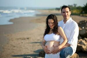 coppia a il spiaggia in attesa per loro bambino - 28 settimane foto