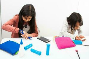 Due giovane ragazze fabbricazione un' giocattolo microscopio con riciclabile Materiale foto