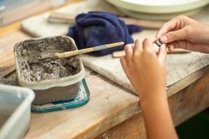 movimento sfocato mani di una ragazza che modella argilla lavorare con fango bagnato in un vassoio di plastica foto