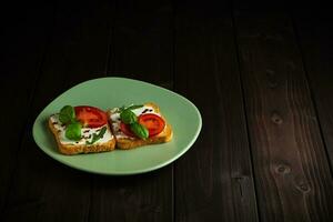 Sandwich fatto di crostini pane, crema formaggio pomodori su un' di legno sfondo. foto