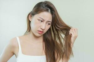 danneggiato capelli, frustrato asiatico giovane donna, ragazza mano nel Tenere scissione finisce, disordinato non spazzolato asciutto capelli con viso shock, lungo spettinato capelli, Salute cura di bellezza. ritratto isolato su sfondo. foto