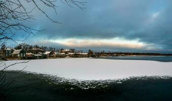 panoramico inverno Visualizza con vecchio case vicino un' innevato lago. autentico settentrionale città di kem nel inverno. Russia foto