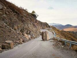 il conseguenze di un terremoto su un' montagna autostrada. grande granito masso abbattere su il strada. pericoloso montagna strada dopo terremoto. pericoloso guida su un' montagna strada durante un' caduta massi. foto