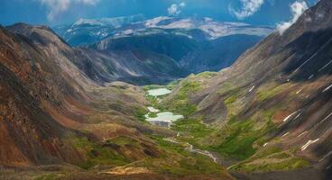 eccezionale alpino panoramico Visualizza a partire dal passaggio per montagna valle nel luce del sole e grande montagna sagome su orizzonte. colorato verde paesaggio con sagome di grande roccioso montagne e epico in profondità gola. foto