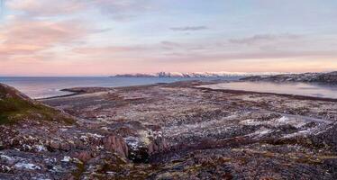 sorprendente Alba polare paesaggio con un' bianca neve cresta di montagne dietro a il roccioso montagne e un' scogliera. meraviglioso panoramico montagna paesaggio con tundra foto