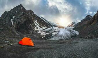 panoramico Visualizza di un arancia fortificato tenda su il sfondo di un' ghiacciaio su un' alta altitudine altopiano. estremo durante la notte restare nel il montagne. foto