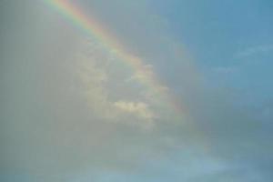 arcobaleno su uno sfondo di cielo blu nuvoloso foto