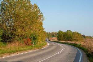 asfalto autostrada nazione strada tra bellissimo autunno colline con cottage foto