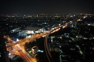 paesaggio urbano della città di notte con le scie luminose dei treni e del traffico su strada foto