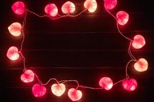 primo piano delle luci a led a forma di cuore decorate in camera oscura foto