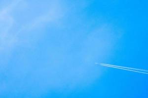 aereo che vola nel cielo azzurro con scia bianca lungo il percorso. getto con scia di condensazione ad alta velocità foto