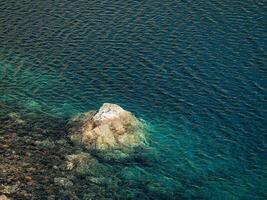 bellissimo natura sfondo di pietroso parte inferiore nel turchese trasparente acqua di glaciale lago nel luce del sole. soleggiato fondale con molti pietre nel verde chiaro acqua di ghiacciaio lago. foto