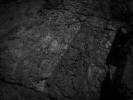 nero pietra sfondo. lungo nero pietra struttura e strutturato. sporco nero pietra parete. roccia struttura con crepe. pietra piastrella pavimento struttura. vecchio parete struttura astratto naturale sfondo. foto