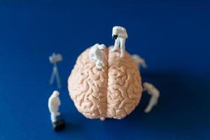 persone in miniatura, scienziati che osservano e discutono del cervello umano, dell'assistenza sanitaria medica e del concetto di servizio medico chirurgico. foto