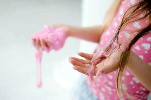 un' poco ragazza macchiato sua capelli con melma. bambino capelli ingarbugliato nel rosa melma. foto