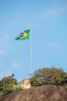 bandiera del brasile in cima alla pietra del timone a rio de janeiro. foto