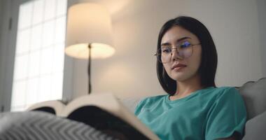 metraggio di contento giovane asiatico donna lettura un' libro foto