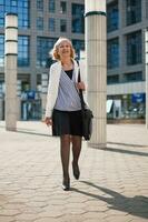 un' anziano donna d'affari a piedi nel il città foto