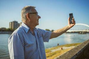 anziano uomo Tenere il Telefono al di fuori foto