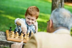 un' nonno e il suo nipote giocando scacchi foto