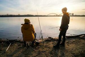 padre e figlio siamo pesca su soleggiato inverno giorno foto