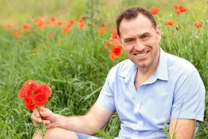 uomo sorridente in un campo di papaveri foto