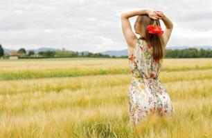 donna in un abito floreale con fiori in un campo