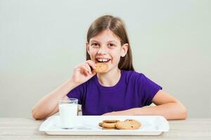 un' ragazza mangiare biscotti con latte foto