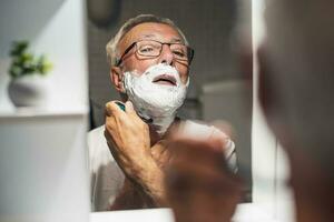 anziano uomo si rade il suo barba foto