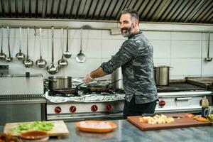 un' capocuoco è preparazione un' pasto nel il del ristorante cucina. foto