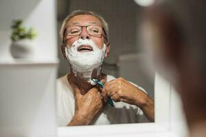 anziano uomo si rade il suo barba foto