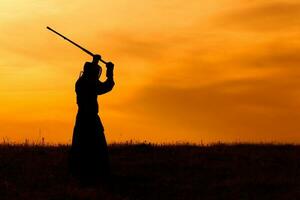 silhouette di kendo combattente con shinai al di sopra di il tramonto foto