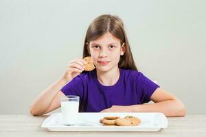 un' ragazza mangiare biscotti con latte foto