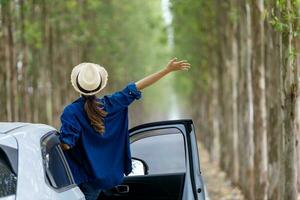 indietro Visualizza di turista donna è godendo su il viaggio su strada mentre avendo vacanza a il nazionale parco guida giù il strada con colonna di albero per viaggio e avventura concetto foto