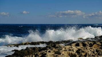 blu mare onda e bianca schiuma e spruzzata. pietra spiaggia su isola di Malta, no sabbioso spiaggia. estate vacanza confine telaio concetto. tropicale isola vacanza sfondo. turista viaggio bandiera design modello. foto