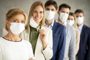 una squadra in fila con una donna che si toglie la maschera foto