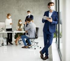 uomo in piedi con una maschera e in possesso di un tablet foto