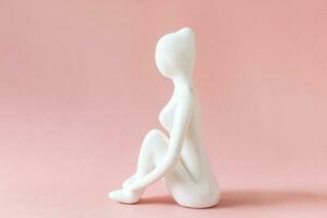 ceramica yoga figurina di donna fare yoga posa su rosa sfondo foto