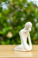 ceramica yoga figurina di donna fare yoga posa su di legno pavimento e verde foglia sfondo foto