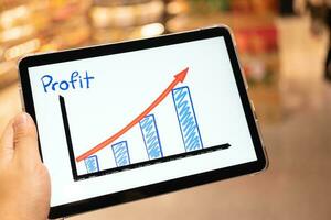 utilizzando tavoletta per vedere attività commerciale crescita predicazione grafico con sfocatura sfondo di Dipartimento negozio. attività commerciale riuscito concetto. concetto di crescita pianificazione e strategia. foto