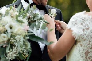 la sposa indossa un fiore all'occhiello con rose bianche per lo sposo foto
