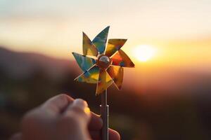 giocattolo mulino a vento nel mano contro un' bellissimo tramonto ai generato foto