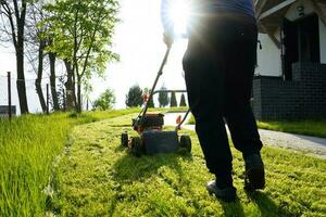 prato falciatura. persona falciatura il erba con arancia taglia erba. falciatura nel il estate su soleggiato giorno. foto