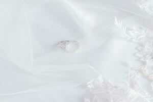 superiore Visualizza di Due diamante platino Fidanzamento anelli su un' bianca elegante raso sfondo con morbido onde e perle. nozze sfondo. foto