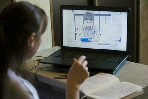 indietro Visualizza di insegnante parlando con alunno nel video conferenza. insegnante e alunno utilizzando il computer portatile per in linea apprendimento nel video chiamata. scolari studiando a partire dal casa. foto