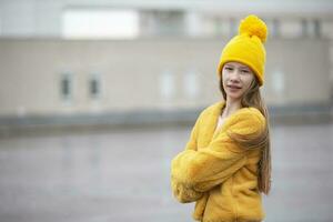 adolescenziale ragazza nel un' giallo cappello e pelliccia cappotto nel freddo tempo atmosferico. foto